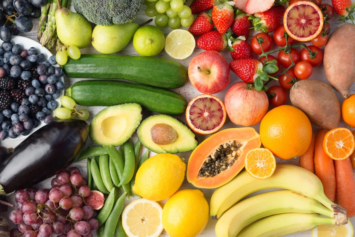 Frutas y verduras de colores variados sobre una mesa: cítricos, frutillas, palta, zucchini y uvas.